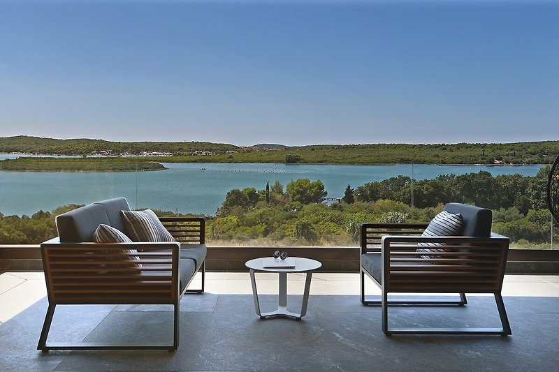 Schöne Terrasse mit bequemen Möbeln und Blick auf den See.