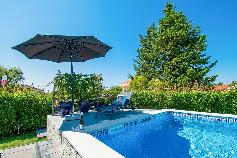 Schwimmbecken mit Sonnenschirmen und Outdoor-Möbeln.