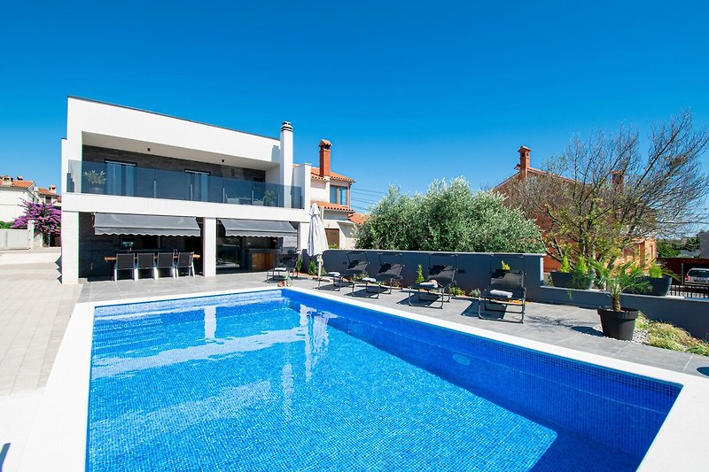 Schönes Ferienhaus mit Pool, blauem Himmel und entspannender Umgebung.