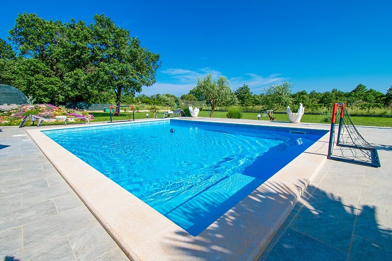 Schwimmbad mit Gebäude, Palmen und Outdoor-Möbeln. Entspannung am Pool.