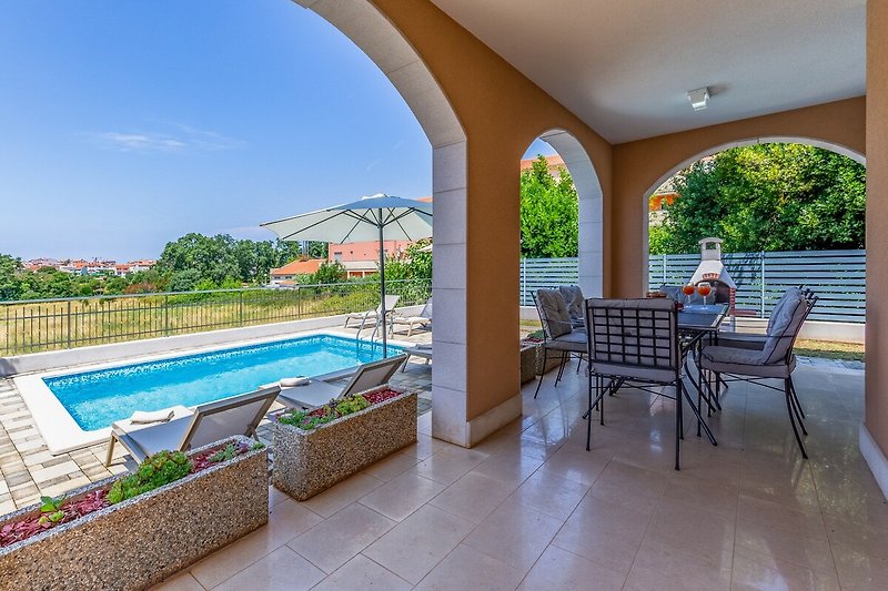 Schwimmbad mit Sonnenliegen und Außenmöbeln in einem Ferienhaus mit herrlichem Ausblick.