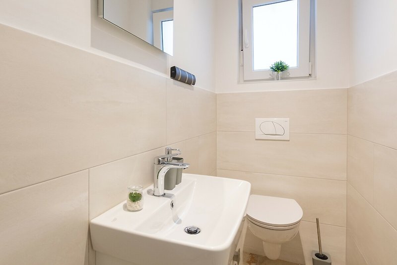 Badezimmer mit Spiegel, Waschbecken und Fenster.