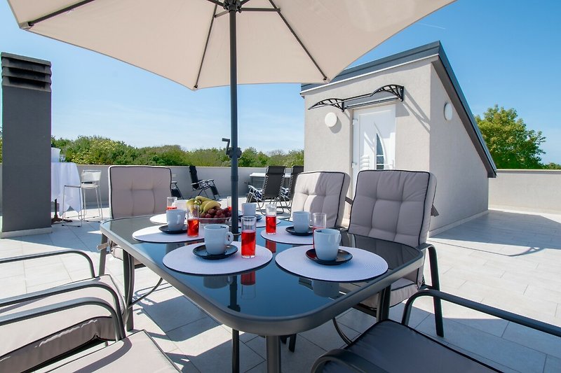 Moderne Terrasse mit stilvollen Möbeln und Sonnenschirm.
