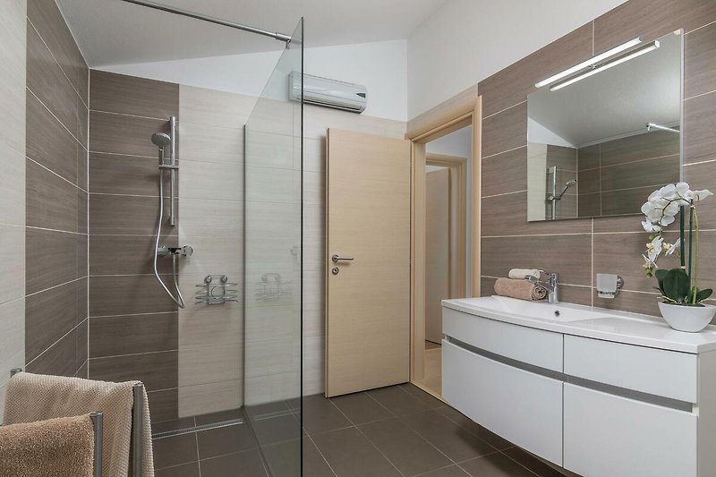 Modernes Badezimmer mit Glasdusche, Spiegel und Armatur. Entspannung pur!