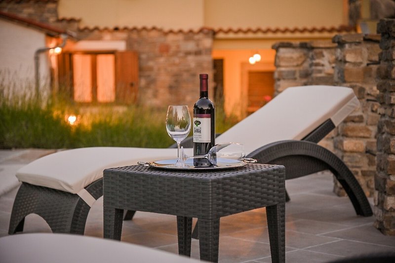 Elegante Terrasse mit Tisch, Stühlen, Wein und Pflanzen.