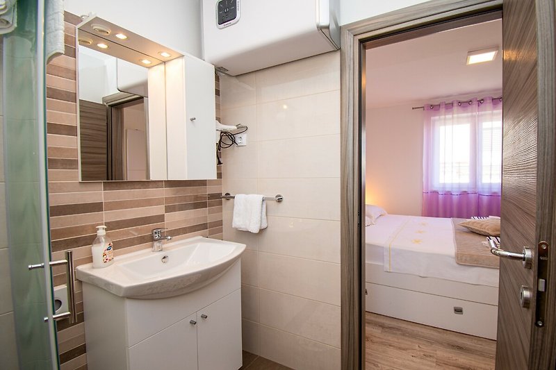 Gemütliches Badezimmer mit lila Holzmöbeln und modernen Armaturen. Entspannen Sie sich und genießen Sie den Komfort.