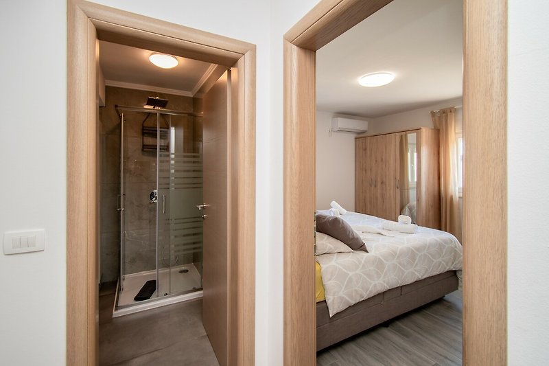 Schlafzimmer mit gemütlichem Bett, Spiegel, Lampen und Fenster.