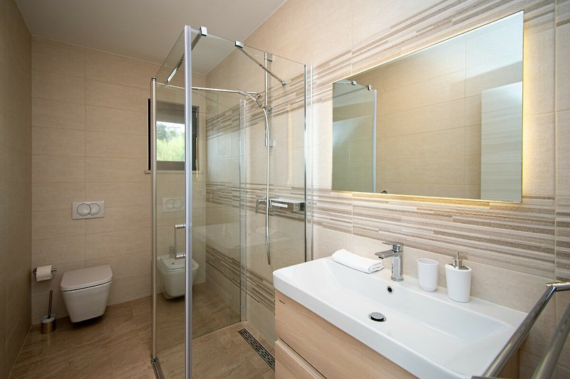 Modernes Badezimmer mit Glasdusche und Aluminiumarmaturen.