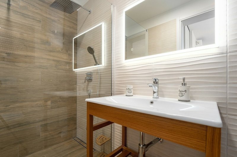 Badezimmer mit Spiegel, Waschbecken und modernem Design.