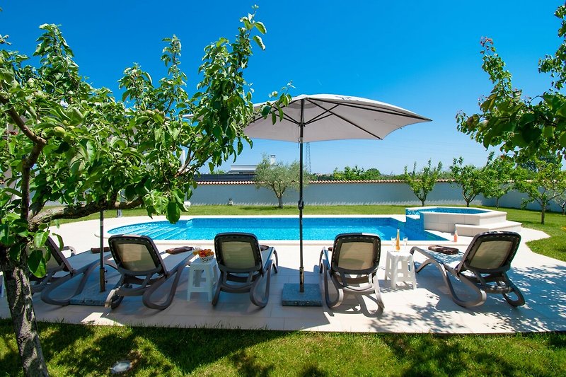 Entspannen Sie sich am Pool und genießen Sie die Sonne, das azurblaue Wasser und die grüne Landschaft.