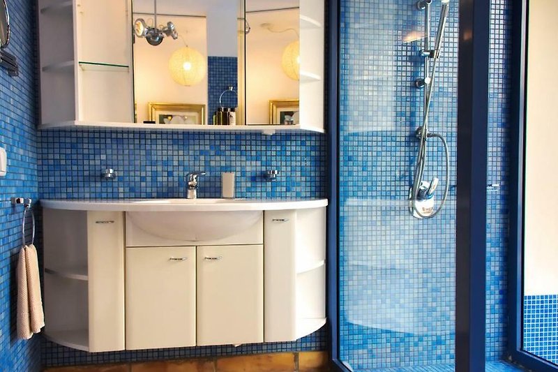 Modernes Badezimmer mit blauer Einrichtung und eleganter Beleuchtung.