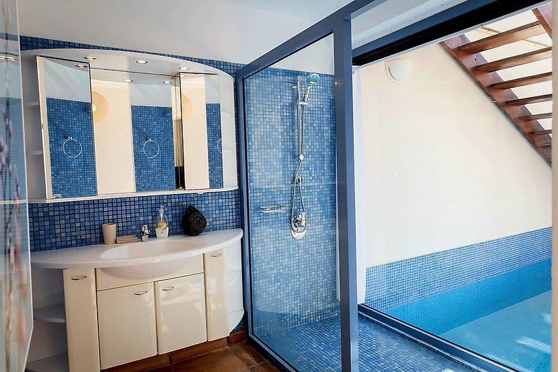 Modernes Badezimmer mit Glasdusche, Holzschrank und Spiegel.