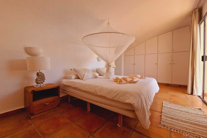 Schlafzimmer mit Holzmöbeln, Bett und Lampen.