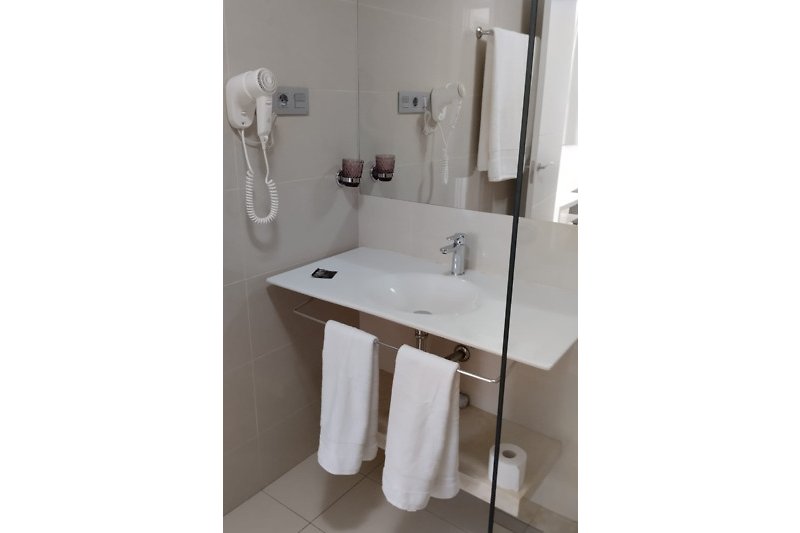 Modernes Badezimmer mit Spiegel, Waschbecken und Fön