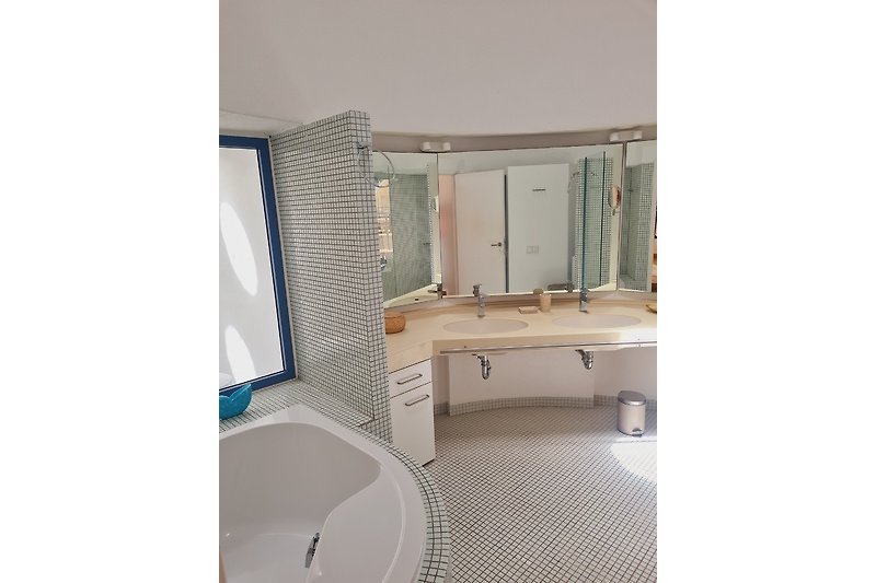 Schönes Badezimmer mit Holzmöbeln, Spiegel und Badewanne.