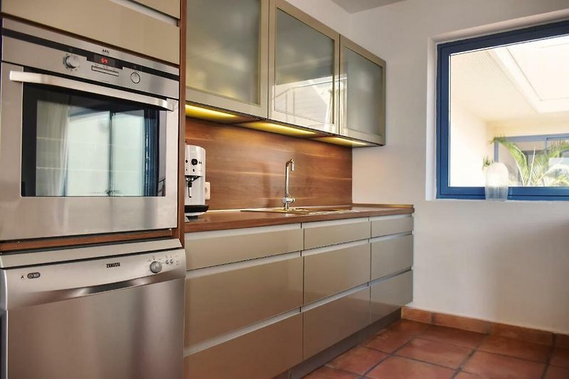 Moderne Küche mit eleganten Schränken, Arbeitsplatte und Fenster.