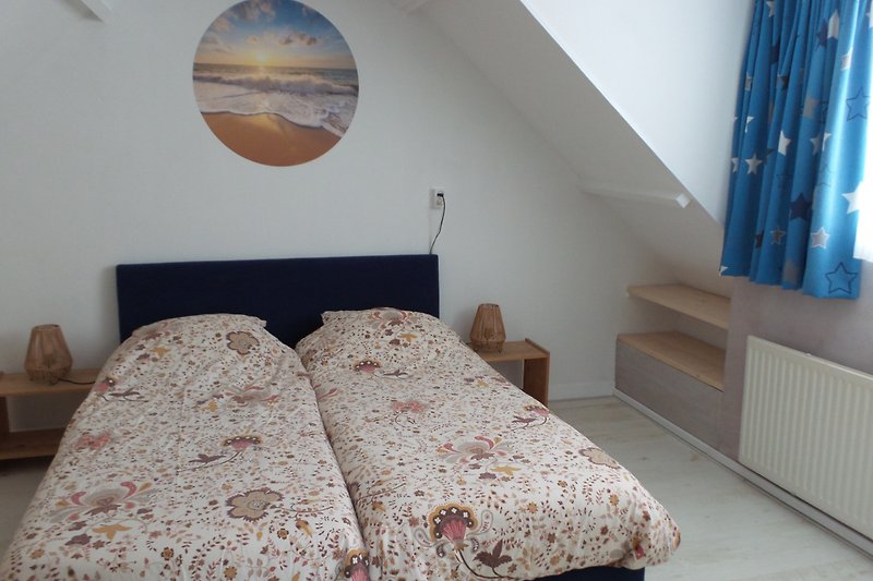 Gemütliches Schlafzimmer mit Holzmöbeln, Bettwäsche und gemütlicher Beleuchtung.