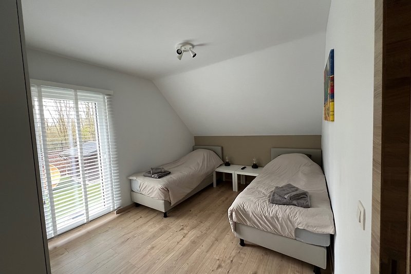 Modernes Schlafzimmer mit Holzbett, Fenster und gemütlicher Beleuchtung.