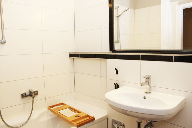 Modernes Badezimmer mit Holzakzenten und elegantem Spiegel.