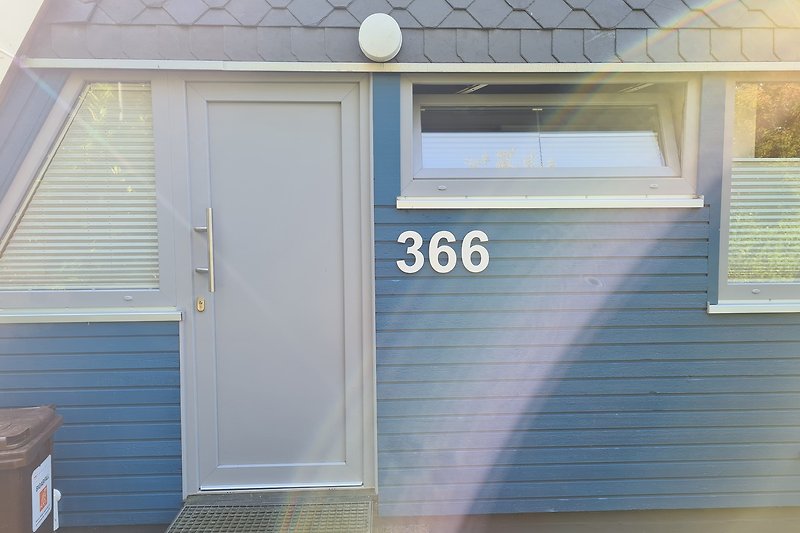Ein charmantes Haus mit blauen Fenstern und einer Holzfassade.
