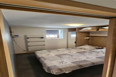 Refugio alpino con balcón y aparcamiento.