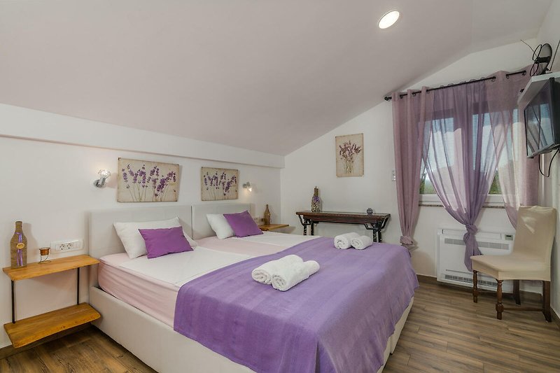 Gemütliches Schlafzimmer mit lila Vorhängen und Holzbett.