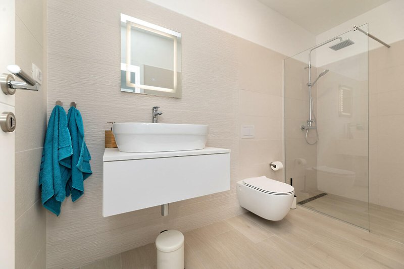 Modernes Badezimmer mit lila Akzenten, Spiegel und Waschbecken.