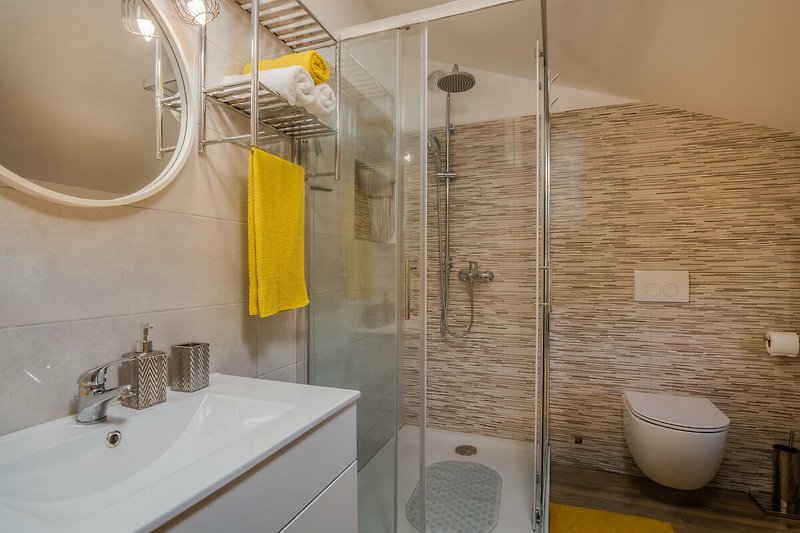 Modernes Badezimmer mit lila Akzenten, Spiegel und Dusche.