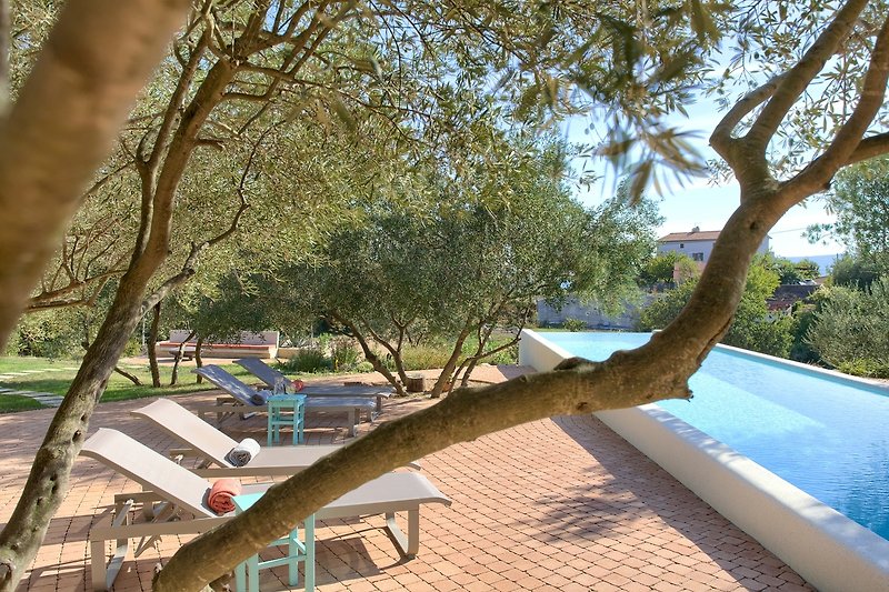 Ferienhaus mit schattigem Baum, Outdoor-Möbeln und Blick aufs Wasser. Entspannen Sie sich in diesem tropischen Resort.