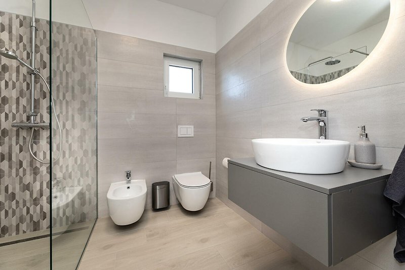 Modernes Badezimmer mit lila Akzenten, Spiegel und Waschbecken.