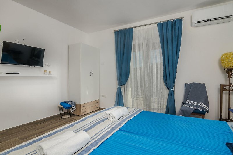 Gemütliches Schlafzimmer mit blauem Vorhang, Holzbett und gemütlichem Bettzeug.
