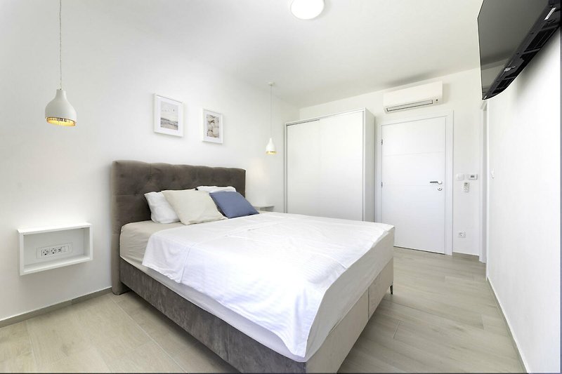 Gemütliches Schlafzimmer mit Holzbett, grauer Wand und stilvoller Beleuchtung.