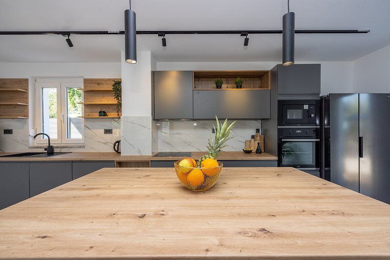 Moderne Küche mit Holzboden, grauen Schränken und stilvoller Beleuchtung.