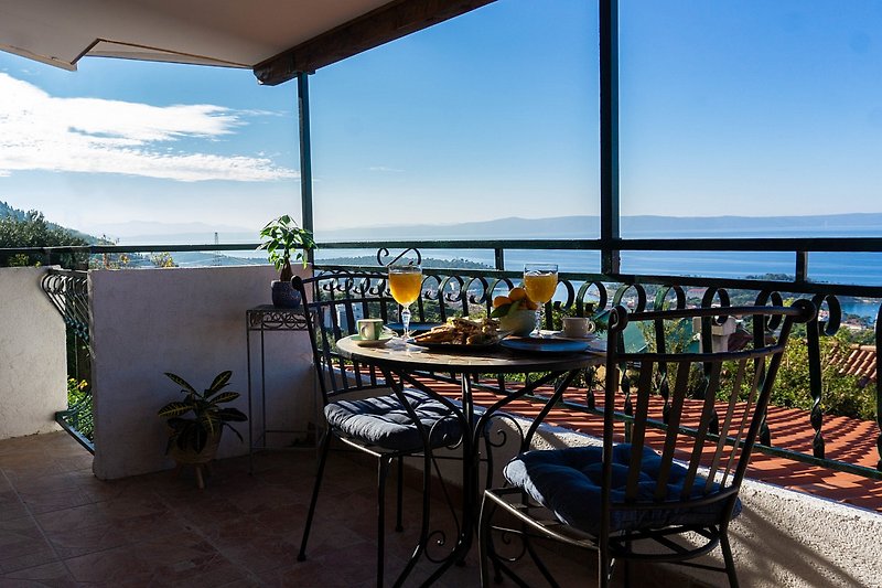 Schöne Aussicht auf das Meer mit Balkon und Außenmöbeln.