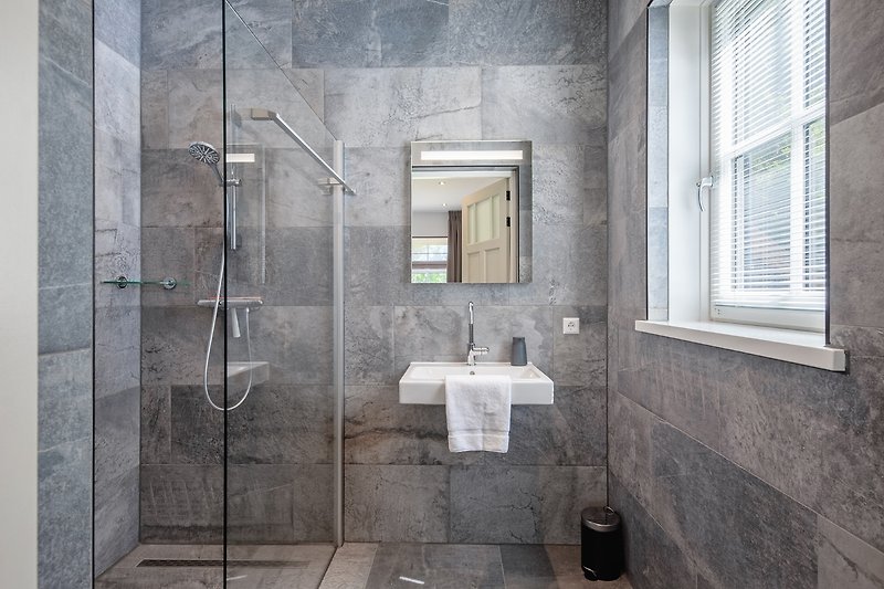 Modernes Badezimmer mit Dusche, Spiegel und Fenster.