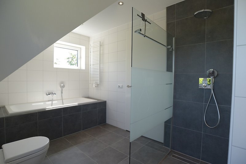 Elegantes Badezimmer mit Dusche, Spiegel und moderner Armatur.