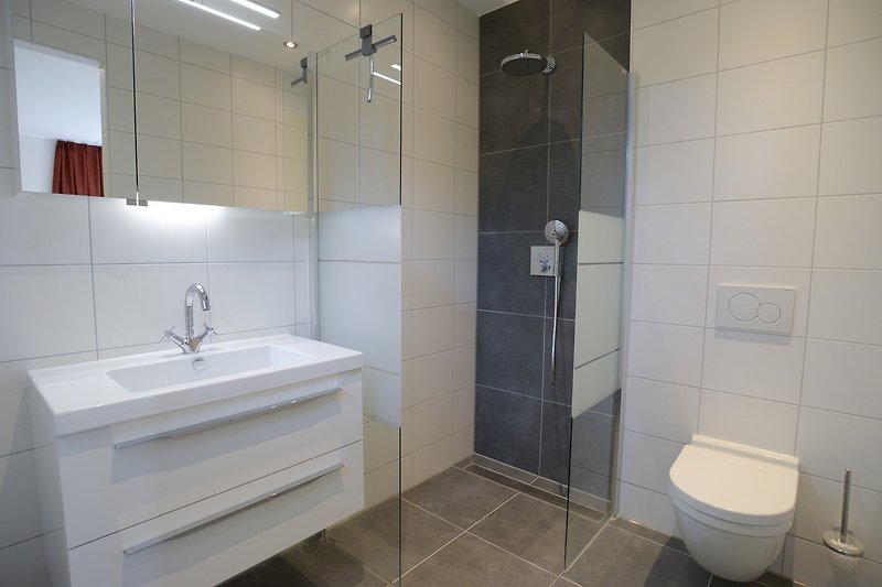 Modernes Badezimmer mit schwarzer Armatur und Spiegel.