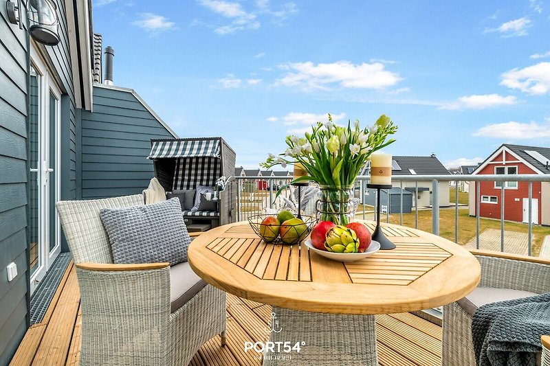 Balkon met uitzicht op een drukke stadstraat, versierd met een kleine tafel en stoelen, omringd door weelderige groene planten en bloemen, waardoor een gezellige en uitnodigende buitenruimte ontstaat.