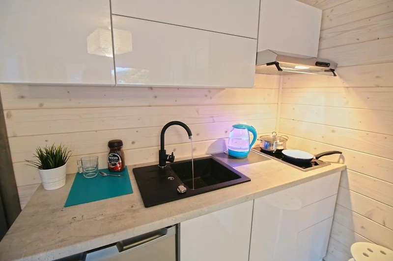 Voll ausgestattete Küche mit Holzdetails, Granit und moderner Beleuchtung.