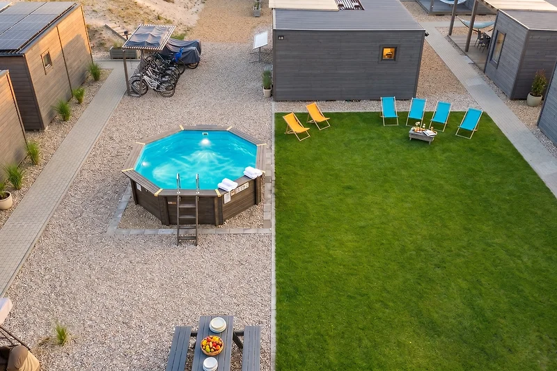 Pool, Whirlpool, Gartenmöbel und Sonnenschirm im begrünten Hof.
