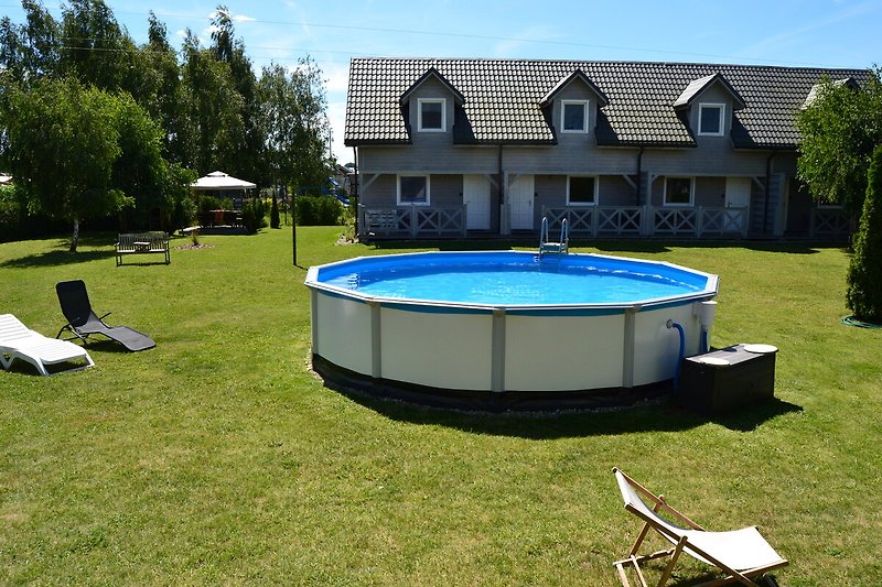 Gebäudeansicht mit Pool und Sonnenliegen  im Garten.