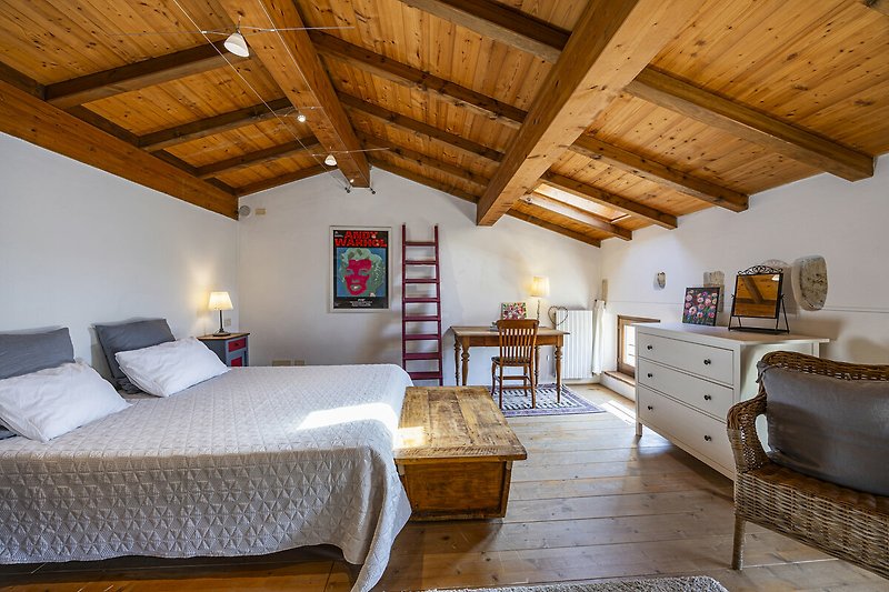 Una stanza con arredamento in legno, finestra luminosa e letto confortevole.