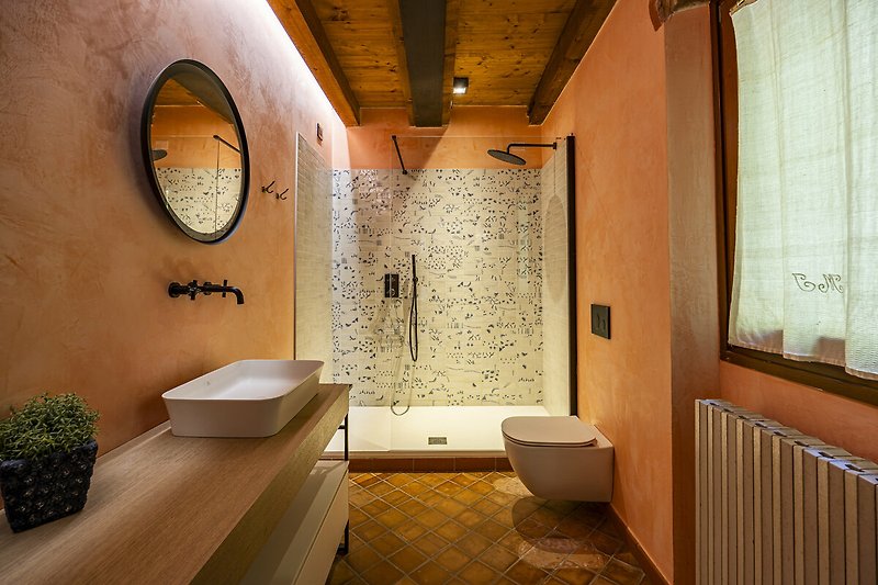 Un bagno moderno con specchio, lavello e piante verdi.