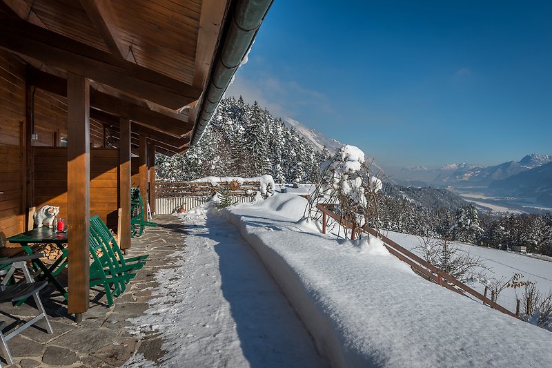 Beeindruckende Berge, schneebedeckte Pisten und ein gemütliches Haus in den Alpen.