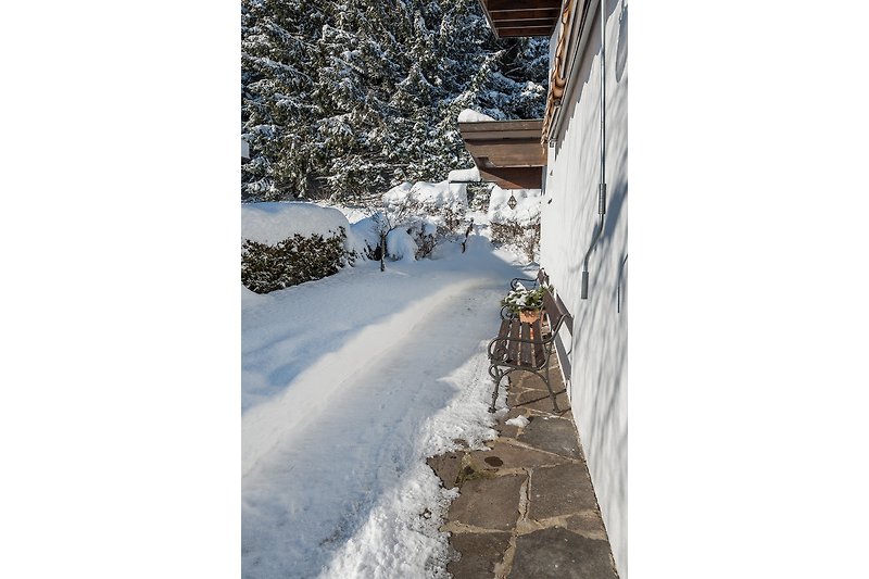 Ein winterliches Haus mit verschneiter Landschaft und Blick auf die Berge.