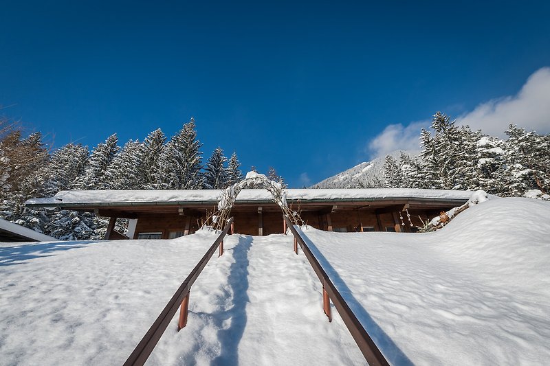 Winterliches Haus mit verschneiter Landschaft und Blick auf die Berge.