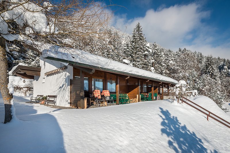 Ein gemütliches Holzhaus in den Bergen mit verschneiter Landschaft.