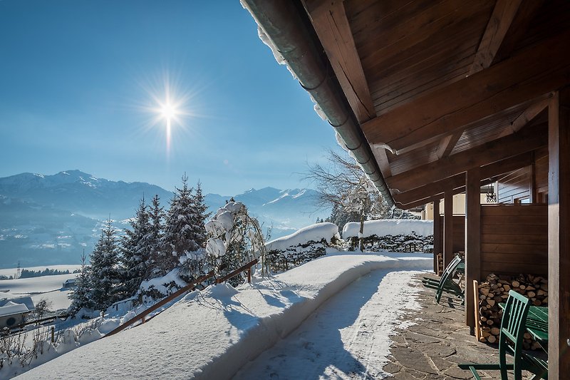 Ein winterliches Haus mit verschneiter Landschaft und Blick auf die Berge.