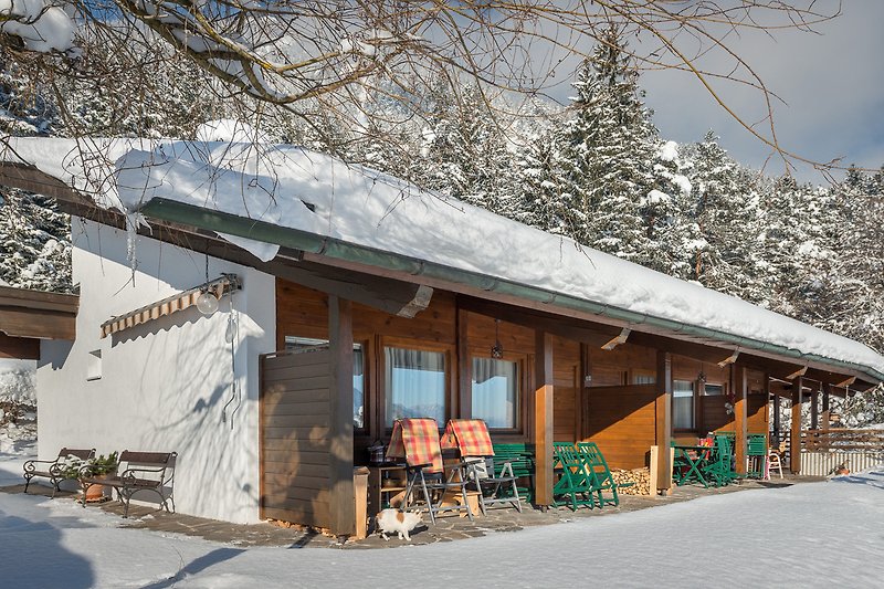 Gemütliches Holzhaus mit verschneiter Landschaft und Blick auf die Berge.