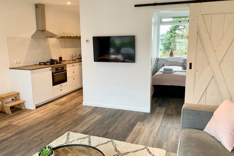 Stilvolles Wohnzimmer mit Holzboden und moderner Küchenausstattung.